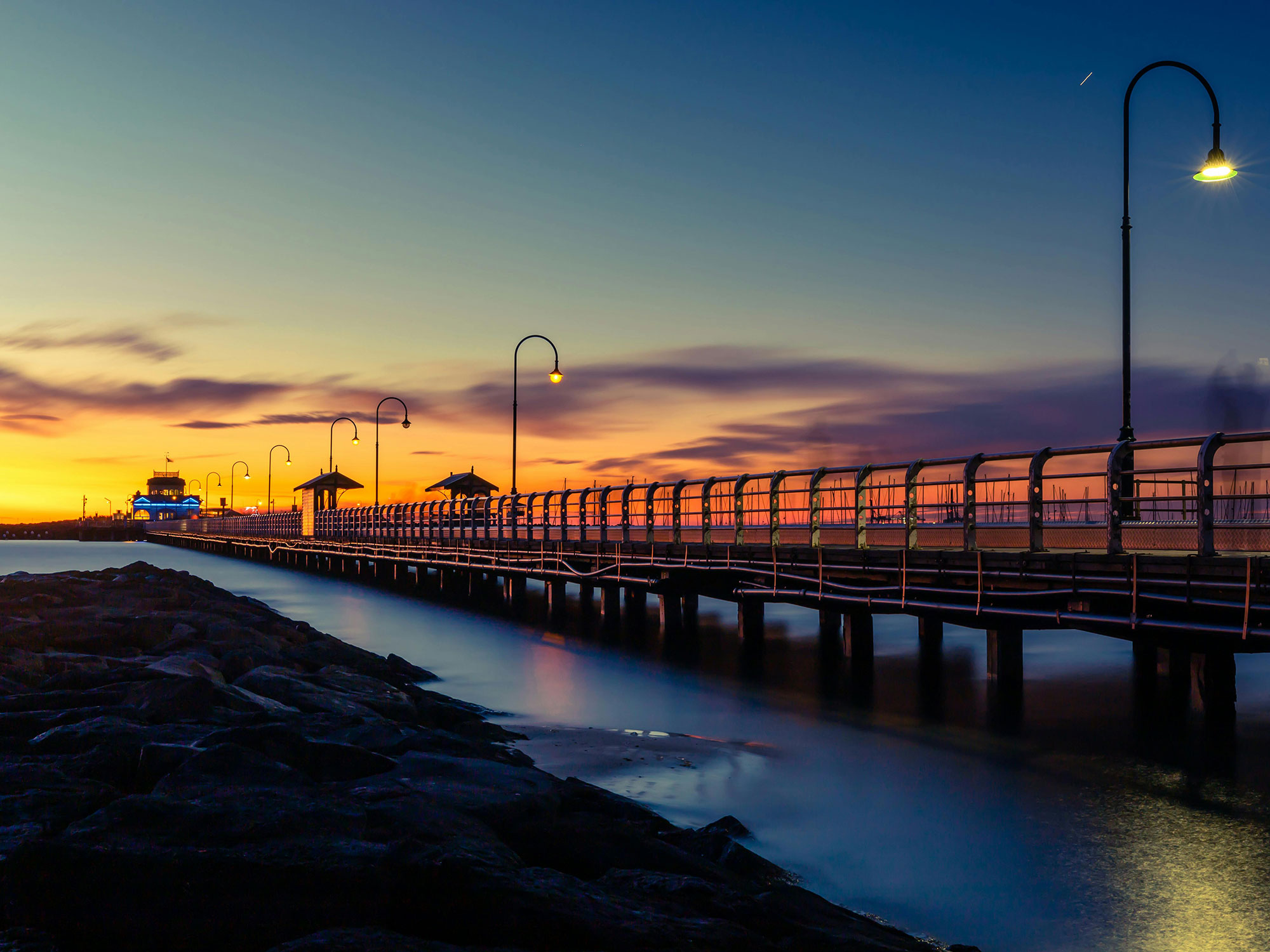 Captivating sunset view of St Kilda Pier in Melbourne with dramatic skies and tranquil water.